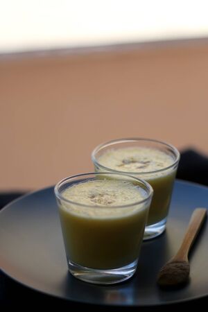 Two glasses of refreshing mango lassi drink, decorated with cardamom. Selective focus.の写真素材