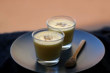 Two glasses of refreshing mango lassi drink, decorated with cardamom. Selective focus.の写真素材