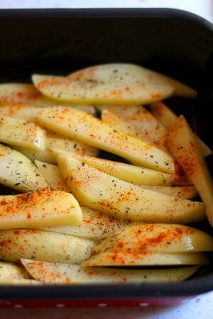 Pan with cut potatoes, dressed with olive oil, basil and smoked paprika. Selective focus.の写真素材
