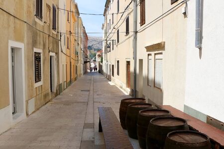 Traditional barrels set as tables on the narrow street of town Pag, island Pag, Croatia.の写真素材