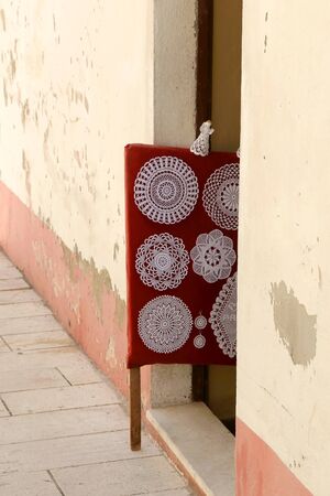 Traditional lace work on display on the narrow street of town Pag, island Pag, Croatia. Pag is famous for its traditional intricate lace.の写真素材