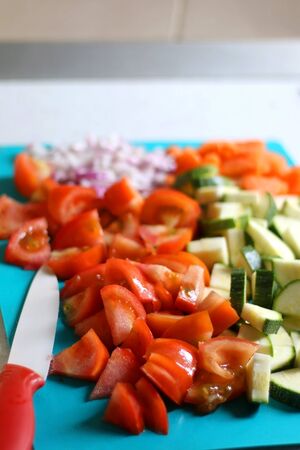 Chopped vegetables on a cutting board: tomato, zucchini, carrot and onion. Selective focus.の写真素材