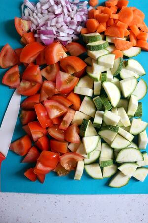 Chopped vegetables on a cutting board: tomato, zucchini, carrot and onion. Top view.の写真素材