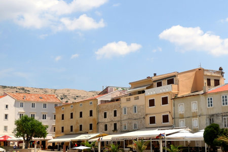 Pag, Croatia - July 7, 2019: Coast of town Pag, on island Pag, Croatia, with traditional architecture and small boats. People enjoying sunny summer day.のeditorial素材