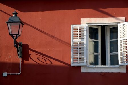 Retro lantern and traditional Mediterranean window on a colorful facade.