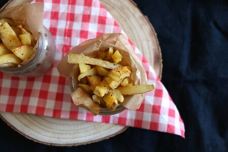 Two portions of homemade baked fries, baked with olive oil and herbs. Top view, dark background.の写真素材