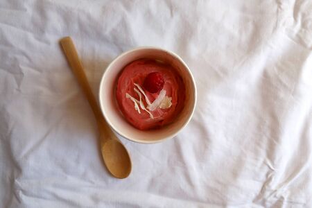 Strawberry vegan ice cream, decorated with raspberry and coconut flakes, in colorful paper cup. Top view.の写真素材