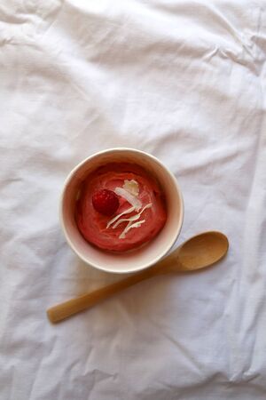 Strawberry vegan ice cream, decorated with raspberry and coconut flakes, in colorful paper cup. Top view.の写真素材