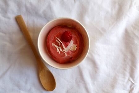 Strawberry vegan ice cream, decorated with raspberry and coconut flakes, in colorful paper cup. Top view.の写真素材
