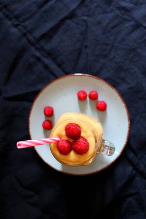 Mango and banana smoothie decorated with raspberries and reusable straw. Top view.の写真素材