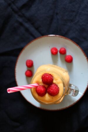 Mango and banana smoothie decorated with raspberries and reusable straw. Top view.の写真素材