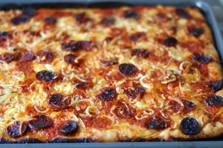Homemade pizza with tomato sauce, parmesan cheese, pepperoni, chorizo and onion. Selective focus.の写真素材