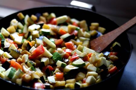 Stir frying seasonal vegetables in a wok. Chopped zucchini, tomato, eggplant and carrot. Selective focus.の写真素材