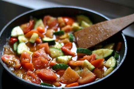 Cooking vegetables in a pan: zucchini, tomato and carrot. Selective focus.の写真素材