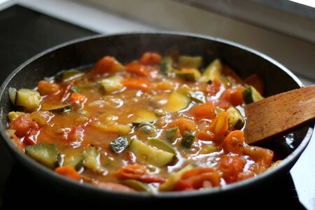 Cooking vegetables in a pan: zucchini, tomato and carrot. Selective focus.の写真素材