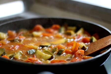 Cooking vegetables in a pan: zucchini, tomato and carrot. Selective focus.の写真素材
