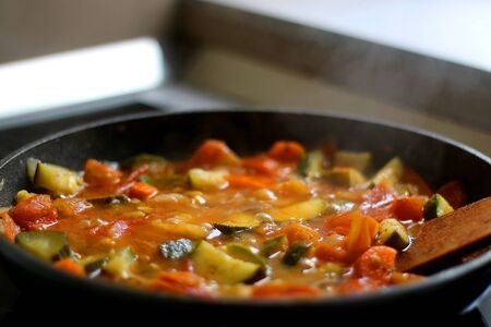 Cooking vegetables in a pan: zucchini, tomato and carrot. Selective focus.の写真素材