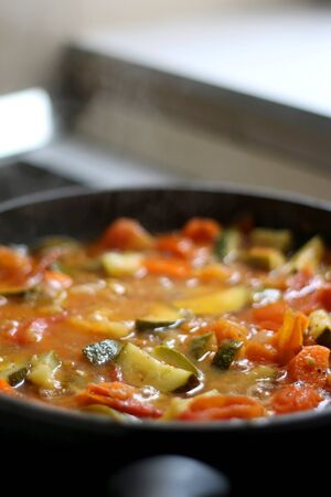 Cooking vegetables in a pan: zucchini, tomato and carrot. Selective focus.の写真素材