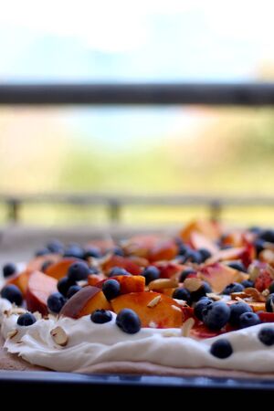 Chocolate Pavlova cake with whipped cream, peaches, blueberries and almonds. Selective focus.の写真素材