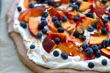 Chocolate Pavlova cake with whipped cream, peaches, blueberries and almonds. Selective focus.の写真素材