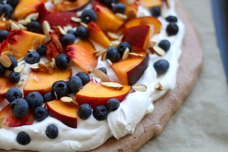 Chocolate Pavlova cake with whipped cream, peaches, blueberries and almonds. Selective focus.の写真素材