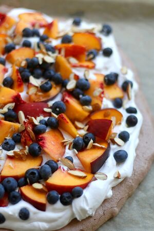 Chocolate Pavlova cake with whipped cream, peaches, blueberries and almonds. Selective focus.の写真素材