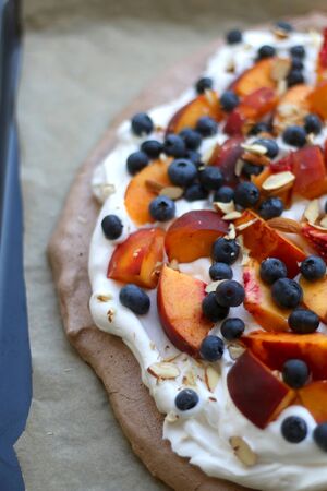 Chocolate Pavlova cake with whipped cream, peaches, blueberries and almonds. Selective focus.の写真素材