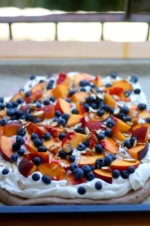 Chocolate Pavlova cake with whipped cream, peaches, blueberries and almonds. Selective focus.の写真素材