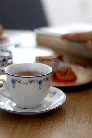Cup of coffee and slice of homemade sponge cake served on a table with whipped cream, cooked apricots and walnuts. Selective focus.の写真素材