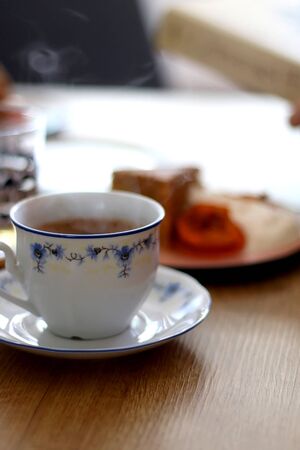 Cup of coffee and slice of homemade sponge cake served on a table with whipped cream, cooked apricots and walnuts. Selective focus.の写真素材