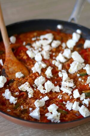 Pot of orzo pasta, with tomato sauce, vegetables and feta cheese. Selective focus.の写真素材