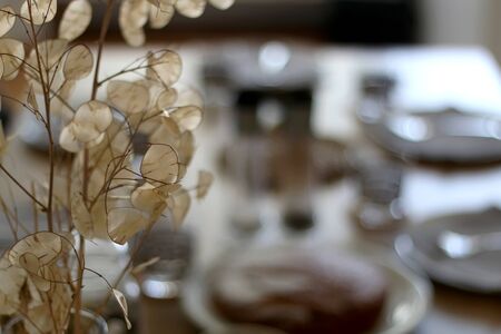 Vase with dry flowers on the table, with dishware and served food in the background. Selective focus.の写真素材