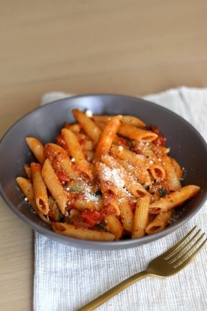Plate of pasta with tomato sauce and eggplant, sprinkled with grated parmesan. Selective focus.の写真素材