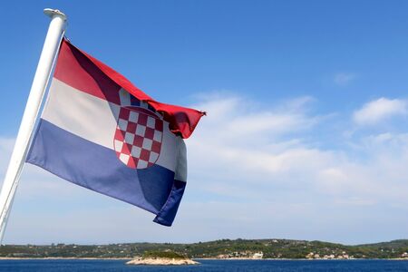 Flag of Croatia blowing in the wind. Croatian coast and islands in the background.の写真素材