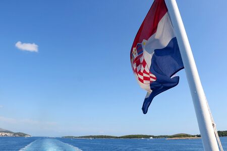 Flag of Croatia blowing in the wind. Croatian coast and islands in the background.の写真素材