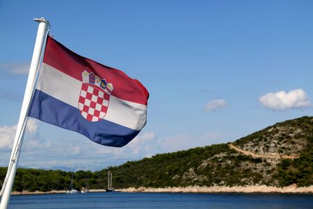 Flag of Croatia blowing in the wind. Croatian coast and islands in the background.の写真素材