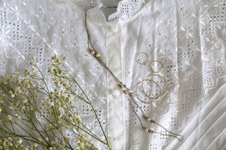 Vintage white lace blouse, silver and gold jewelry and white gypsophila flowers. Top view.の写真素材