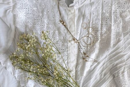 Vintage white lace blouse, silver and gold jewelry and white gypsophila flowers. Top view.の写真素材