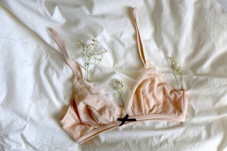 Pale pink bralette and gypsophila flowers on white sheets. Top view.の写真素材