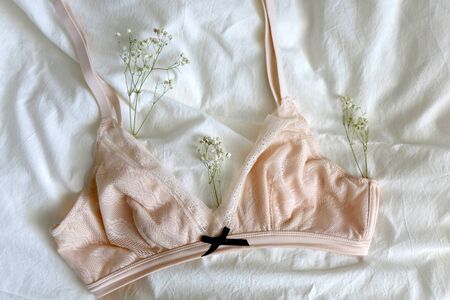 Pale pink bralette and gypsophila flowers on white sheets. Top view.の写真素材
