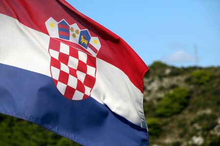 Flag of Croatia blowing in the wind. Hill and bright sky in the background. Selective focus.の写真素材