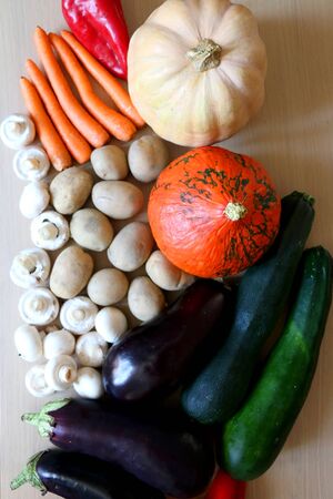 Pile of vegetables on a wooden table: pumpkin, squash, carrots, potatoes, eggplants, courgettes, peppers and mushrooms. Top view.の写真素材