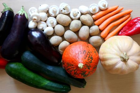 Pile of vegetables on a wooden table: pumpkin, squash, carrots, potatoes, eggplants, courgettes, peppers and mushrooms. Top view.の写真素材