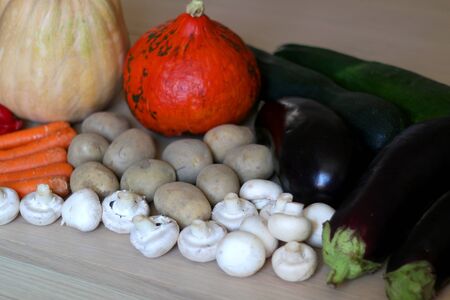 Pile of seasonal vegetables on wooden table: pumpkin, squash, zucchini, potato eggplant, pepper, carrot and mushroom. Selective focus.の写真素材