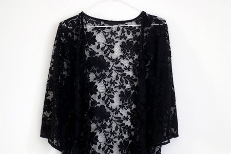 Black lace kimono top hanging in front of white wall.の写真素材