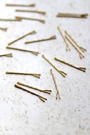 Gold colored hair pins on a marble background. Selective focus.の写真素材