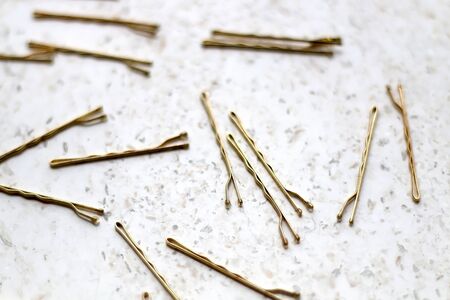 Gold colored hair pins on a marble background. Selective focus.の写真素材