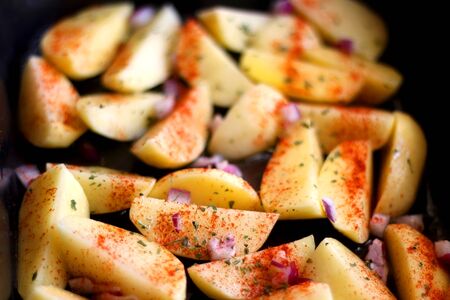 Cut potatoes seasoned with purple onion, basil and smoked paprika. Selective focus.の写真素材