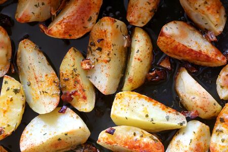 Baked potatoes seasoned with onion, basil and smoked paprika. Top view.の写真素材