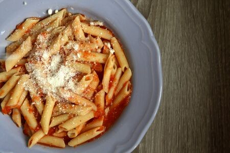 Plate of pasta with homemade tomato sauce. Sprinkling parmesan cheese on top. Flat lay.の写真素材